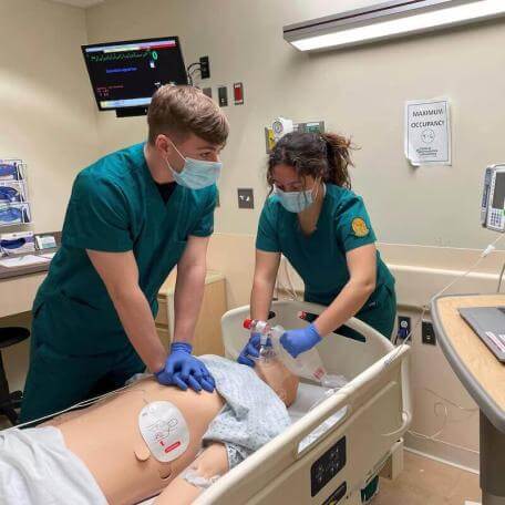 UVM nursing students practice lifesaving CPR techniques on a mannequin during training