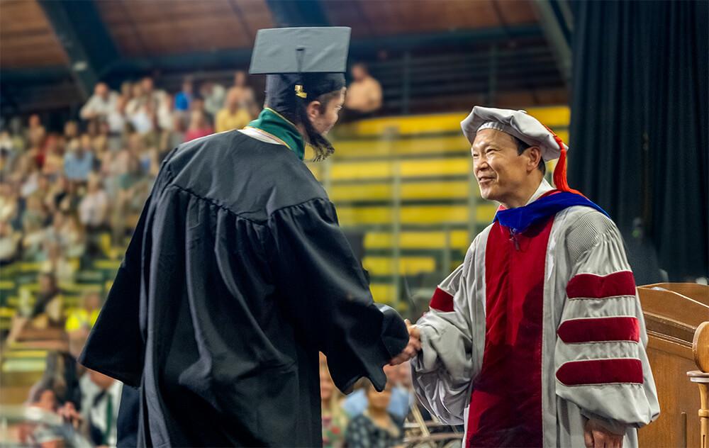 Mathematics and Statistics department chair Jianke Yang congratulates a graduate during the 2024 commencement